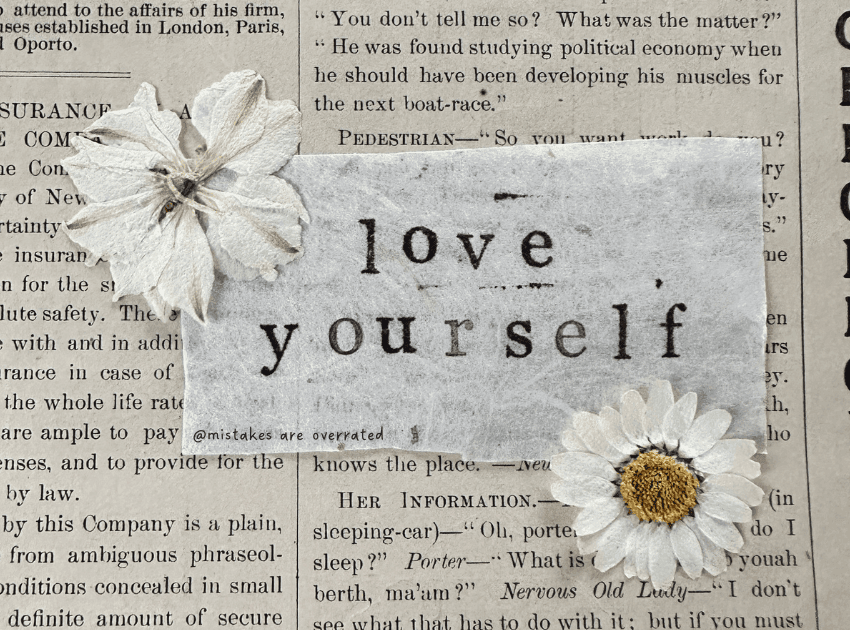 'love yourself' sticker over newspaper