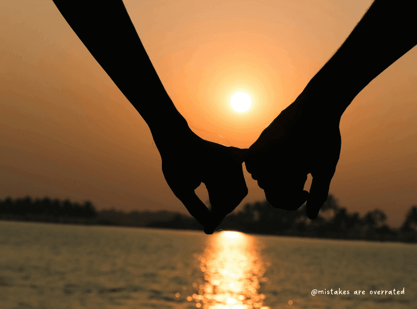 hands holding in front of sunset